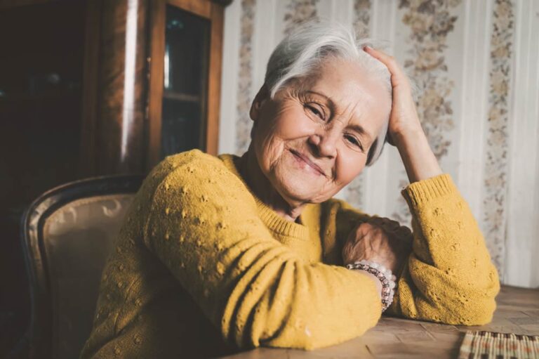 Woman in a yellow sweater smiles at the camera