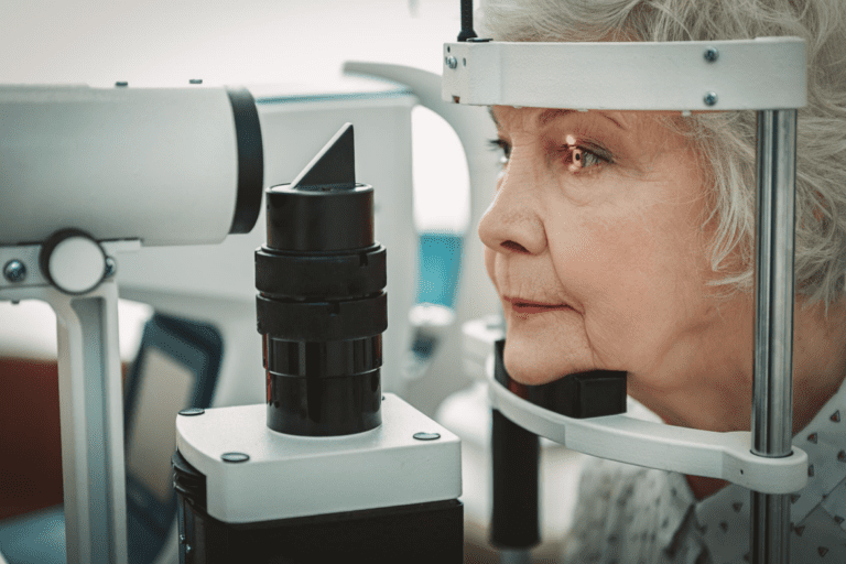 A senior woman is having an eye examination using specialized ophthalmic equipment.