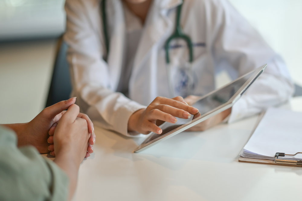 A doctor talking to a patient and using a tablet