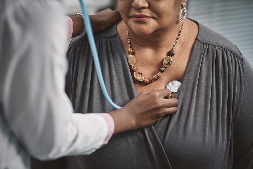 A doctor using a stethoscope on her patient