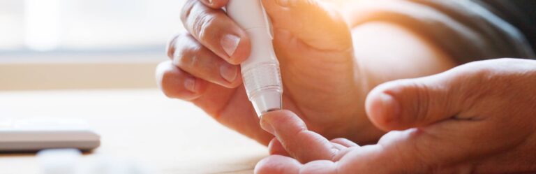 A person uses a medical lancet device to prick their finger for blood testing.