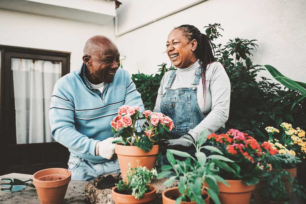 A man and a woman gardening on their porch