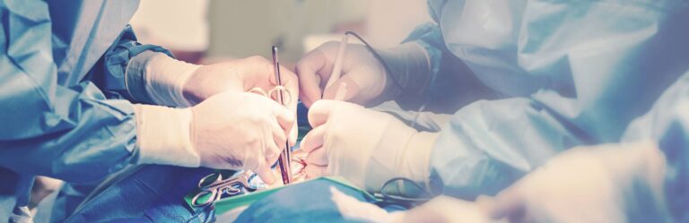 Surgeons perform a medical procedure in an operating room, with hands wearing gloves and holding surgical instruments.