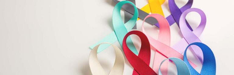 A variety of awareness ribbons in different colors are arranged on a light background, representing various causes and health conditions.