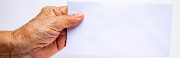 A hand holding a blank white envelope on a plain background.