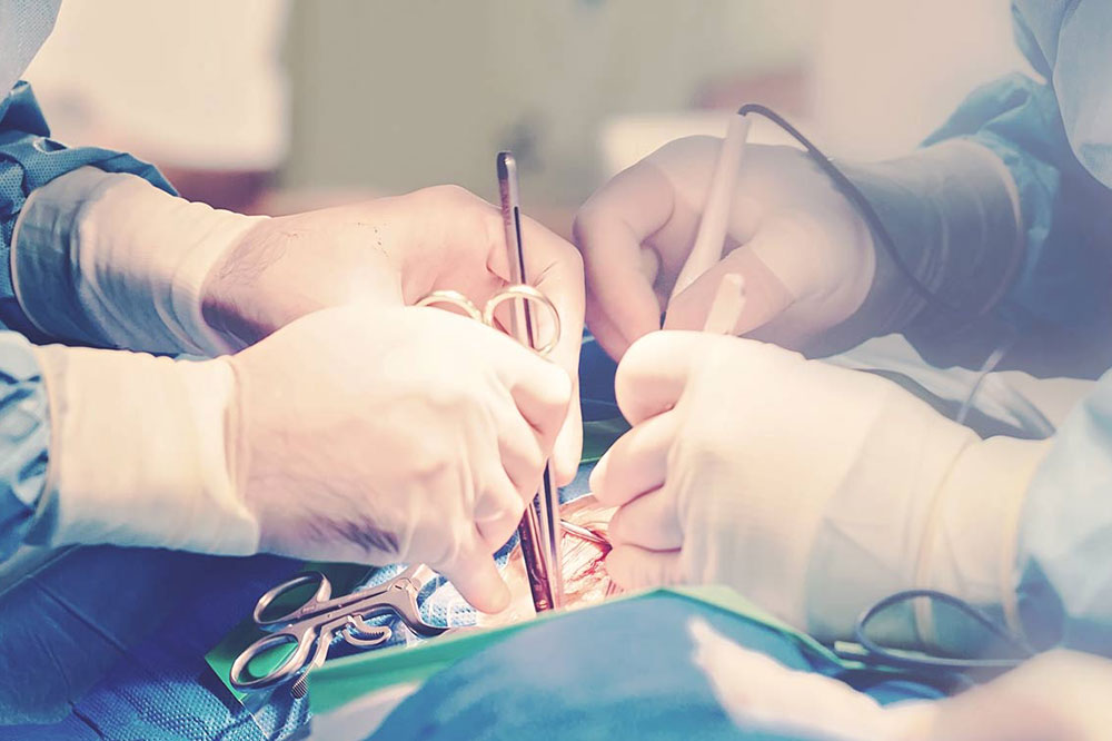 Close-up of surgeons' hands in gloves, performing a surgical procedure with various medical instruments in an operating room.