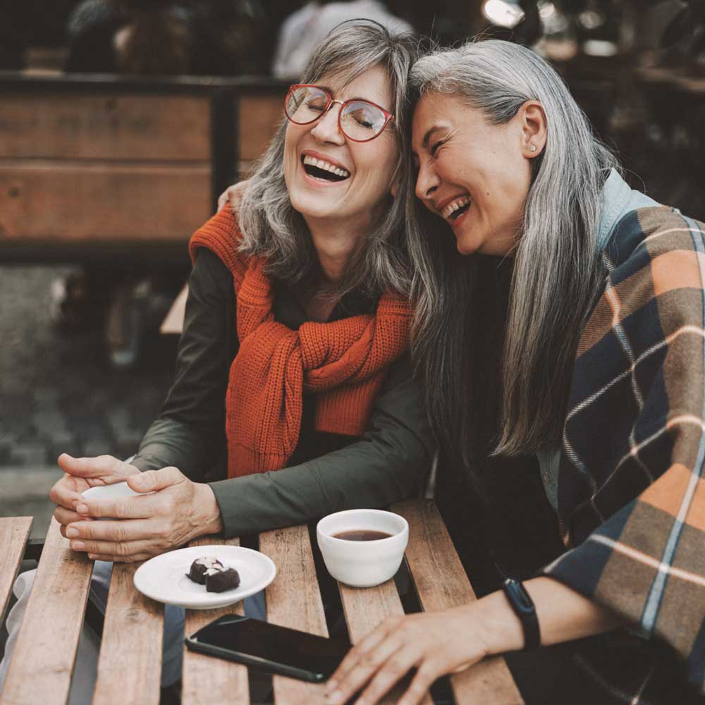 Two friends laughing over coffee