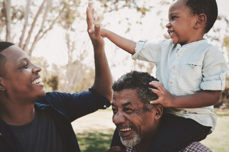 Laughing grandfather with his young grandson on his shoulders.