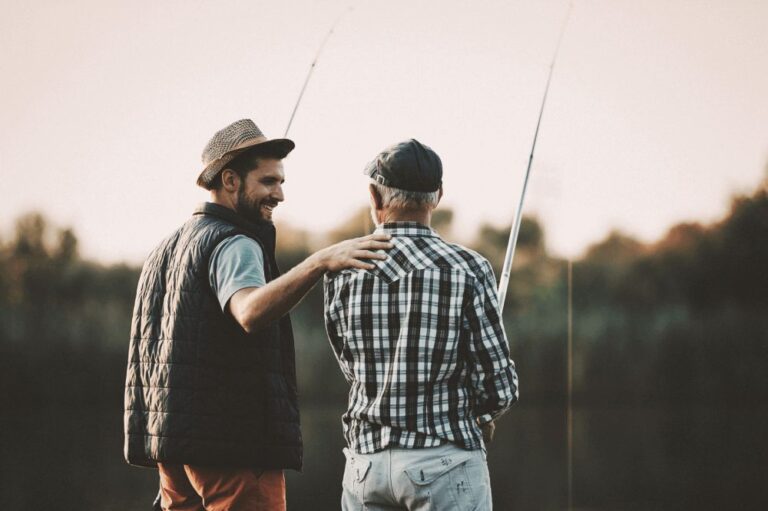 Adult son fishing during dusk with his father