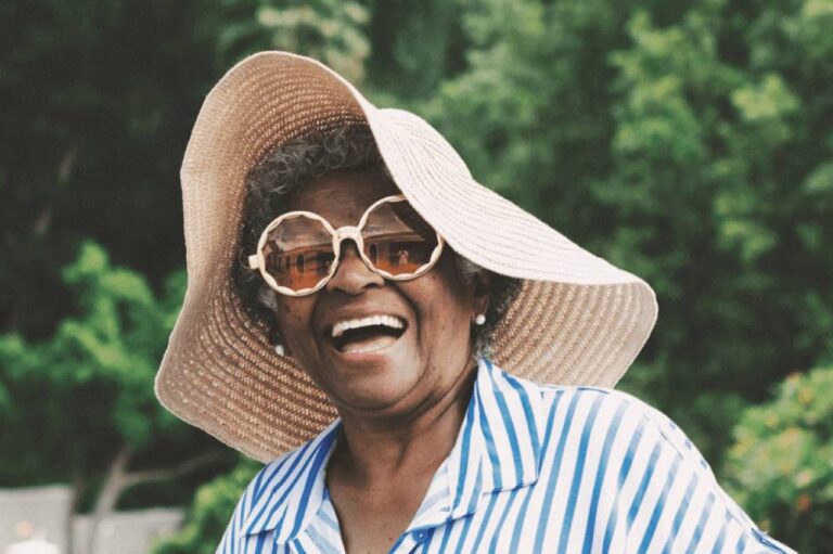 Smiling woman with large straw sunhat and round glasses