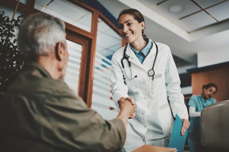 Smiling female doctor shaking hands with seated patient